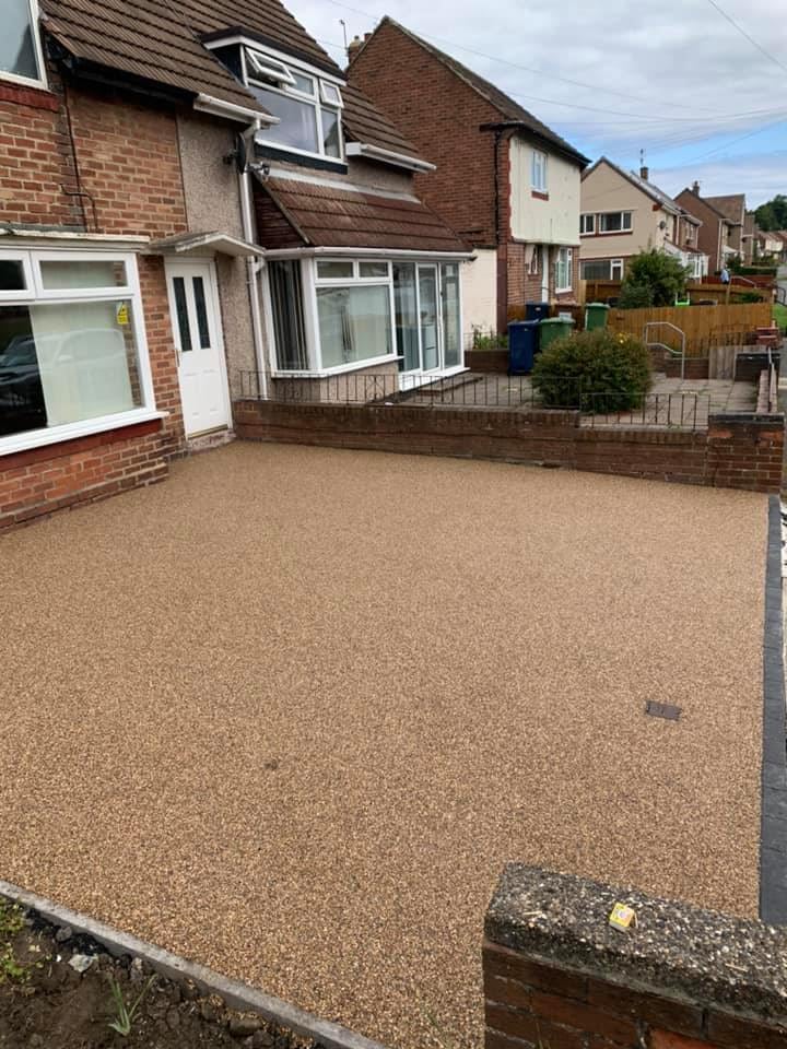 Golden resin driveway outside a red brick home